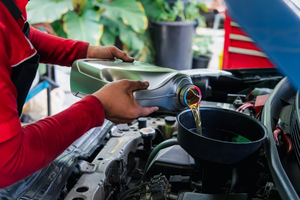 Garage automobile, deux mécaniciens en combinaisons bleues travaillent sous un véhicule surélevé